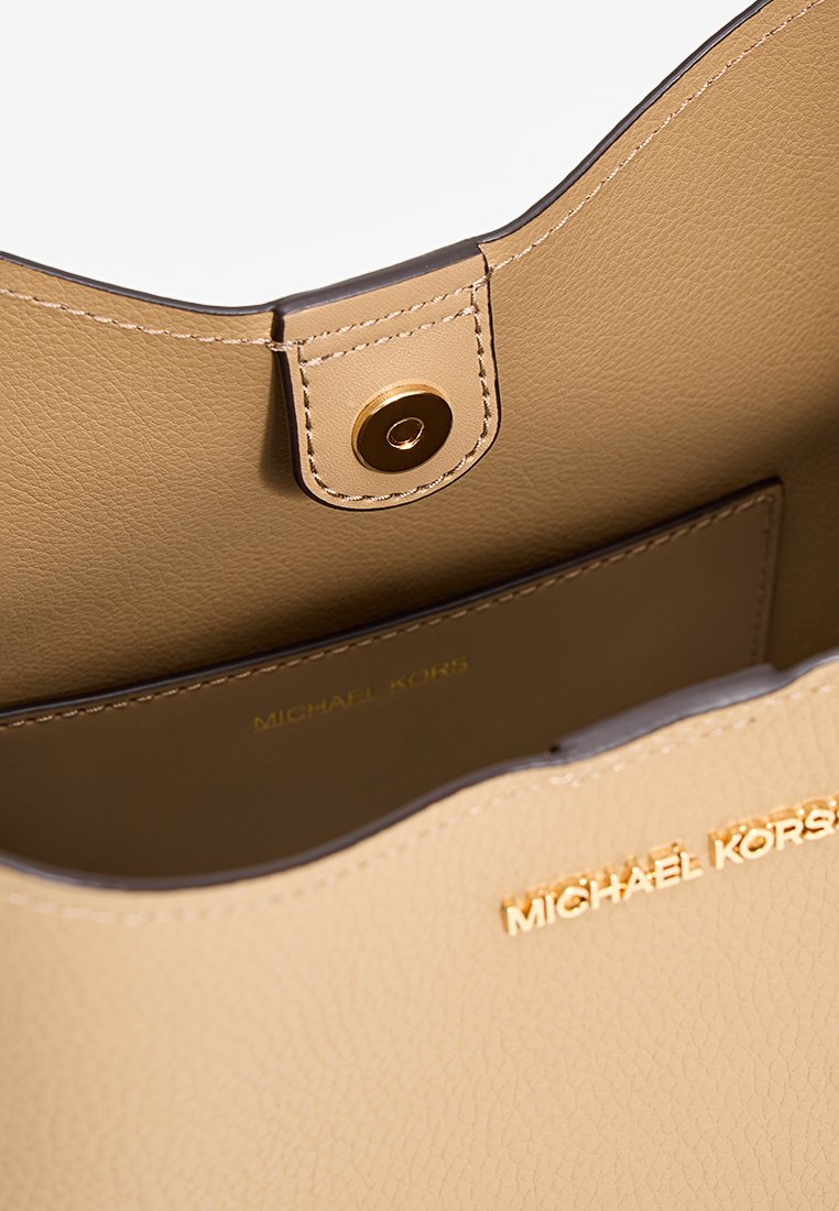 Beige leren handtas met een gladde textuur, gouden hardware sluiting en subtiele reliëflogo aan de binnenkant. Gebogen bovenrand en gestructureerd ontwerp.