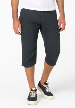 Black knee-length cargo shorts with a textured finish, featuring side pockets and stitched accents, paired with dark sneakers.