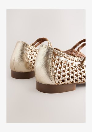 Zapatos de cuero trenzado dorado con punta redondeada y un tacón bajo marrón, presentan un trenzado intrincado y un acabado metálico liso.