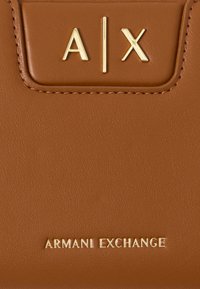 Καφέ πορτοφόλι από τεχνητό δέρμα που διαθέτει ανάγλυφα χρυσά γράμματα "A|X" και "ARMANI EXCHANGE" στην πρόσοψη, με υφασμάτινες λεπτομέρειες.