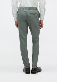 Pelēki rakstaini bikses, izgatavotas no strukturēta auduma, ar taisnu piegriezumu, divām aizmugurējām kabatām ar pogām un jostasvītru ar jostu cilpiņām.