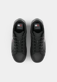 Zapatillas negras con parte superior de cuero suave, puntera redondeada y diseño de cordones. Presenta acentos texturizados y una etiqueta con el logo en la lengüeta.