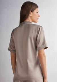 Kortärmad, mjuk satinskjorta i taupe med kontrasterande ljus kant och krage, som har en slät textur och avslappnad passform.