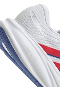 Chaussure de sport blanche avec des accents rouges et bleus, inscription "Response 2" sur l'empeigne, et amorti "Cloudfoam+" sur la semelle intermédiaire blanche avec une semelle extérieure bleue.