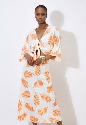 Robe blanche avec des motifs de feuilles orange, dotée d'un design à nouer à l'avant et de manches larges, fabriquée en tissu léger.