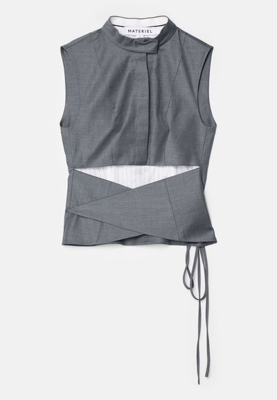 Gray sleeveless top with a high collar, featuring a wrap design and side ties, made of textured fabric with a striped underlay.