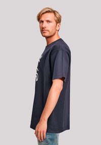 Navy blue cotton t-shirt with short sleeves and crew neck, featuring white graphic text on the front. Casual fit with a straight silhouette.