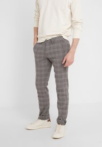 Grå rutig byxor med slim fit, med ett subtilt mönster, sidofickor och uppvikta nederkanter, i kombination med vita sneakers.