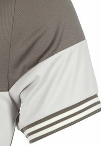 Grijs-wit korte mouwen shirt met een getextureerd bovenstuk, een gladde onderpaneel en gestreepte mouwboorden in contrasterende kleuren.