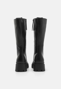 Black leather knee-high boots with a smooth texture, chunky soles, and side zippers. Features a rounded toe and vertical stitching details.