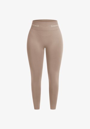 Leggings beige de tejido elástico, con una cinturilla alta que lleva el nombre de la marca "SMIL" en blanco en la parte frontal. Textura suave en general.