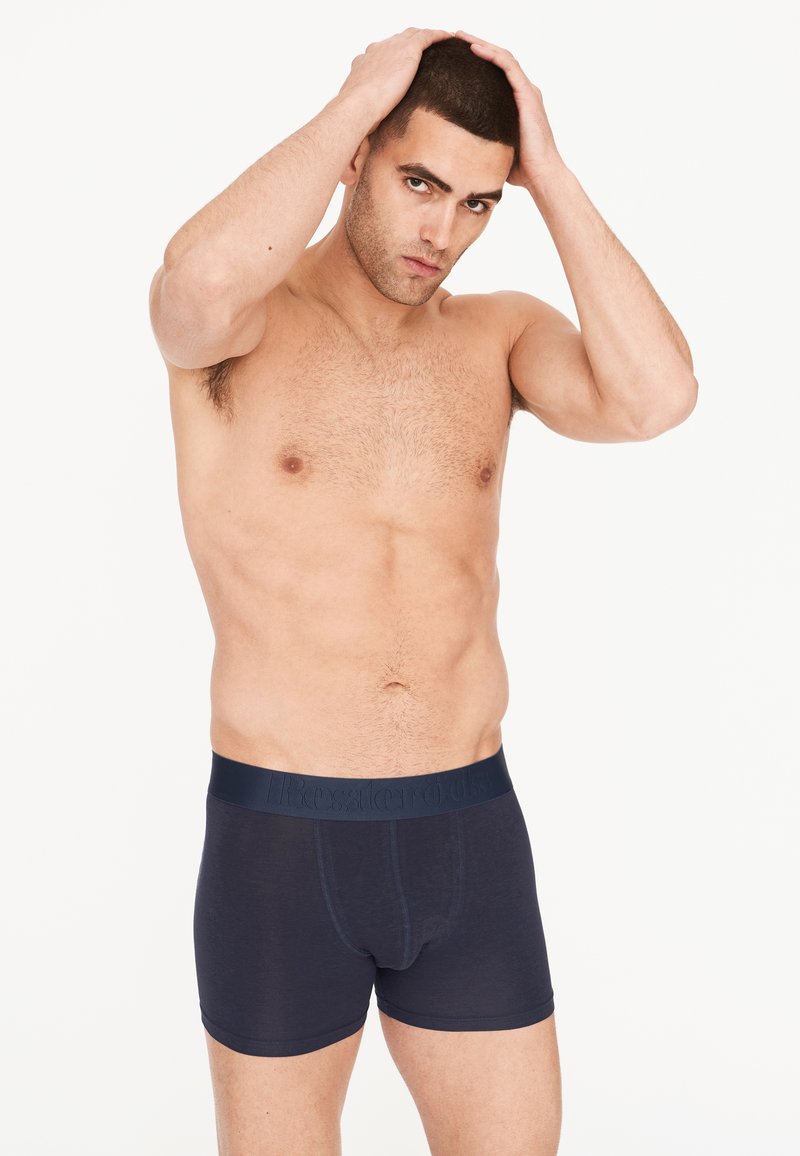 Boxer de color azul marino fabricados con un tejido suave, con una cinturilla elástica con logo en relieve, diseño ajustado y frente sin costuras.