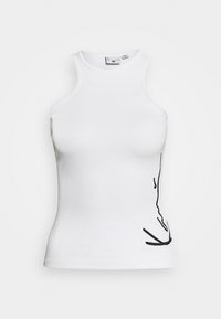 Vit ribbad ärmlös topp med hög halsringning och subtil svart abstrakt linjedesign på nedre högra sidan.