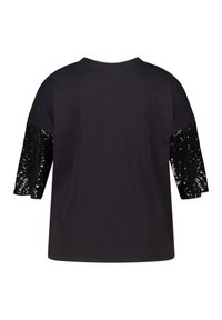 Zwart T-shirt met korte mouwen en een ronde halslijn, versierd met pailletten op de mouwen. Het heeft een zachte stof en een relaxed, losse pasvorm.