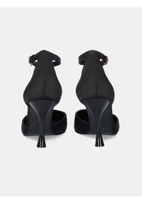 Zapatos de tacón alto negros con un diseño elegante, que cuentan con un material suave, punta afilada y un tacón de aguja delgado. Detalle de cinta en el tobillo posterior.