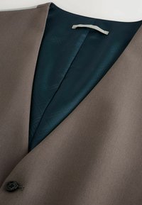 Brauner maßgeschneiderter Blazer mit einem satinartigen Futter in dunklem Tannengrün, das ein geometrisches Muster aufweist. Mit einem einzelnen schwarzen Knopfverschluss und einem eleganten Reversdesign.