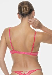 Rosa underkläder i set som innehåller en åtsittande bh med smala band och knäppning, som visar en slät yta och delikata accenter.