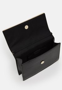 Czarny kopertówka ze wzorem krokodyla z metalowymi elementami w kolorze złotym, z zamknięciem na magnes i pojemnym wnętrzem wyłożonym materiałem.