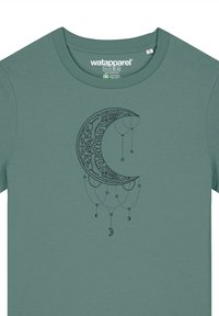 Groene katoen T-shirt met een grafiek van een donkere maan met ingewikkelde details en hangende elementen, gecentreerd op de voorkant.