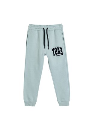 Pantalones jogger de color azul claro en material suave, con cintura elástica y cordón de ajuste, bolsillos laterales y un estampado gráfico negro en la pierna.