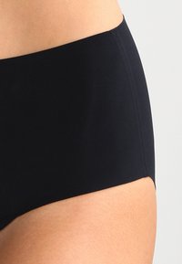 Black high-waisted bikini bottom, made of smooth fabric, featuring a solid design with minimal seams and a clean finish at the waistline.