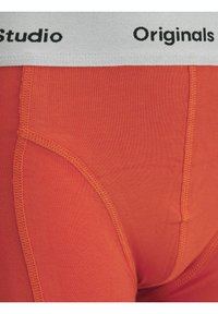 Orange herrboxer i stretchmaterial, med ett mjukt, elastiskt midjeband som har "Studio Originals"-logotypen i svart.
