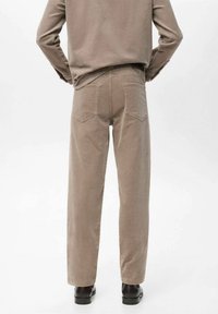 Pantalones de pana marrones con corte recto, que cuentan con dos bolsillos traseros y una superficie texturizada, combinados con botas negras de tobillo.