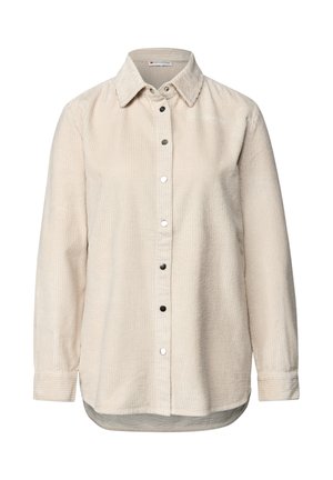 Beige corduroy pitkähihaisessa paidassa on kaulus ja mustat nepparit edessä, ja siinä on hieman kaareva helma.