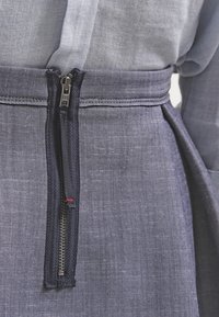 Falda de mezclilla con cremallera vertical, tejido azul oscuro con una textura sutil y una cinturilla ajustada con un acabado suave.