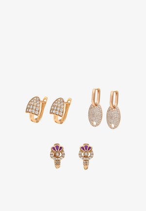 Tre paia di orecchini d'oro: mezzaluna con pietre trasparenti, goccia ovale con dettagli traforati e pietre trasparenti, e design floreale con accenti viola.