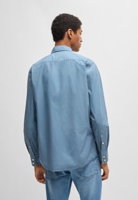 Lichtblauw overhemd met lange mouwen, voorzien van een button-down kraag, knopen bij de manchetten en een relaxte pasvorm. Glad stof met een effen ontwerp.