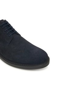 Scarpa da uomo in suede blu navy con punta rotonda, sei occhielli e suola in gomma scura. Texture liscia con dettagli di cucitura minimi.