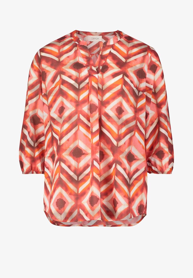 Blouse à manches longues avec motif géométrique en diamants dans des tons de rouge, orange, blanc et marron, dotée d'un col rond et de poignets élastiques.