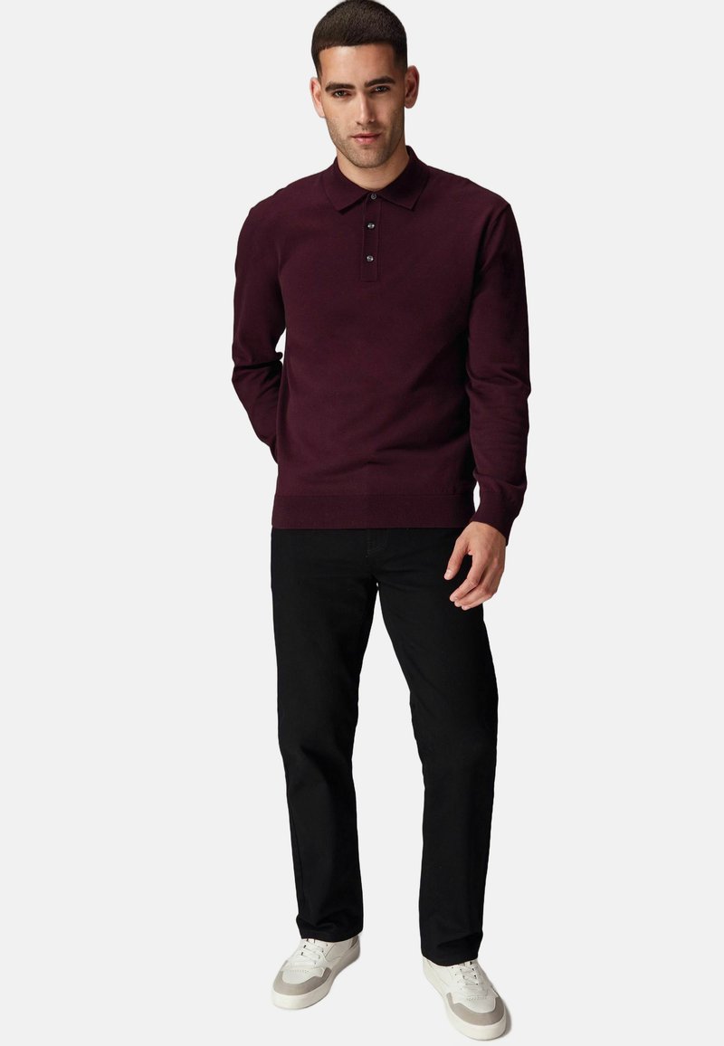 Suéter burdeos con cuello clásico y tapeta de tres botones, combinado con pantalones negros y zapatillas blancas. Tejido suave, puños acanalados.