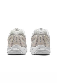 Grå och vita sportskor med överdel i mesh, texturerade detaljer, vadderad sula och logotypdetalj på hälen. Förstärkt bakdel för stöd.