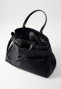 Borsa a tote in pelle nera con superficie testurizzata, doppi manici e un accentuato logo sulla parte anteriore. Design con apertura superiore che rivela un ampio interno.