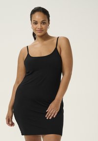 Vestito nero senza maniche realizzato in tessuto liscio, design aderente, lunghezza al ginocchio con un semplice scollatura a girocollo e spalline regolabili.
