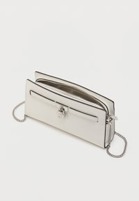 Bela usnjena denarnica s srebrno kovino, z zadrgo na predelu za shranjevanje in okrasnim sprednjim zaponkom. Vključen odstranljiv verižni trak.