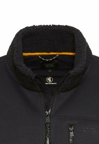 Schwarze Fleecejacke mit einem weichen, strukturierten Kragen in Dunkelgrau und gelbem Futter. Mit einem Reißverschluss vorne und seitlichen Taschen mit Reißverschlüssen.