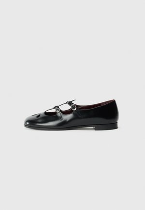 Chaussures plates en cuir noir avec deux sangles réglables, bout rond et découpes à l'avant. Texture lisse et talon bas.