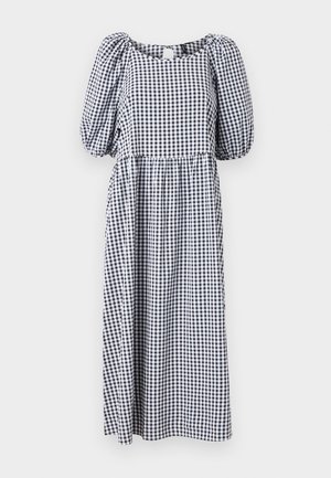 Svart och vit rutad klänning, knälång, med puffärmar och fyrkantig halsringning. Tillverkad av lätt tyg med gathered midja.