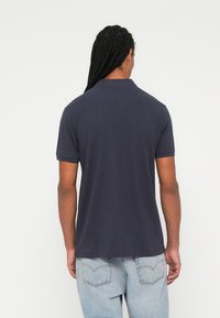 Mørkeblå polo skjorte med korte ærmer og klassisk krave, lavet af glat stof, parret med lyseblå denim jeans.