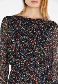 Schwarzes Kleid mit Paisley-Muster in Rot, Blau und Creme. Mit langen Ärmeln und einem gerafften Taillenbund für Form und Struktur.