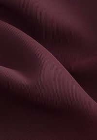 Burgundy textured fabric with vertical ribbed pattern, showing smooth, flowing drape and soft appearance.