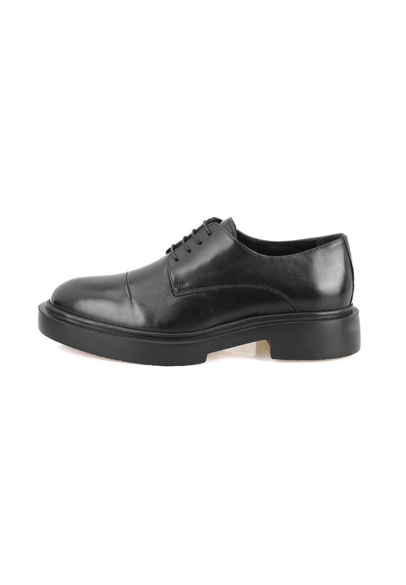 Zwarte leren oxford schoen met een gladde afwerking, ronde neus, zes oogjes voor vetersluiting en een dikke zwarte rubberen zool.