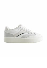 Sneakers bianchi caratterizzati da un mix di texture lisce e scamosciate, un design low-top, accenti neri a contrasto e una spessa suola in gomma bianca.