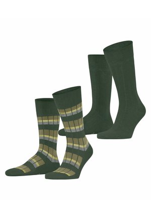 Due paia di calzini verdi, uno verde scuro tinta unita e uno con motivo a quadri giallo e grigio, in piedi su uno sfondo bianco.