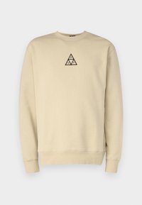 Felpa beige con colletto rotondo, polsini a costine e un logo triangolare ricamato in nero sul petto. Tessuto morbido, design casual.