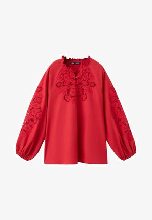 Blouse rouge à manches longues avec broderie en dentelle florale sur la poitrine et les manches, encolure à volants et patte de boutonnage à l'avant.