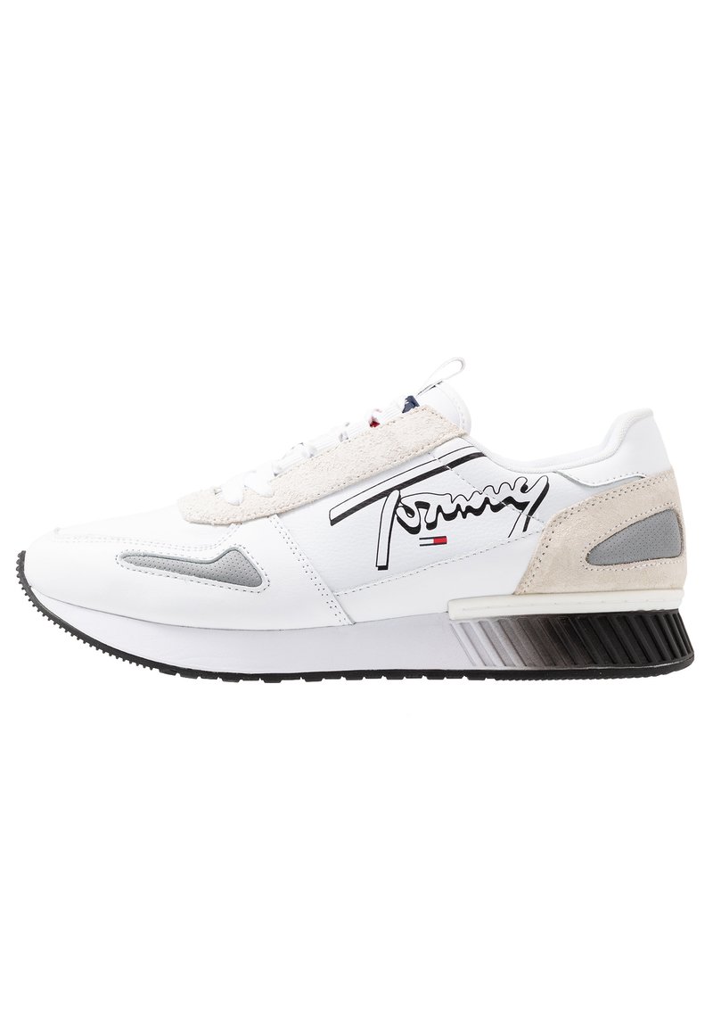 Białe sneakersy z cholewką wykonaną ze skóry i zamszu, z czarną gumową podeszwą, szarymi akcentami oraz wyraźnym logo z boku.